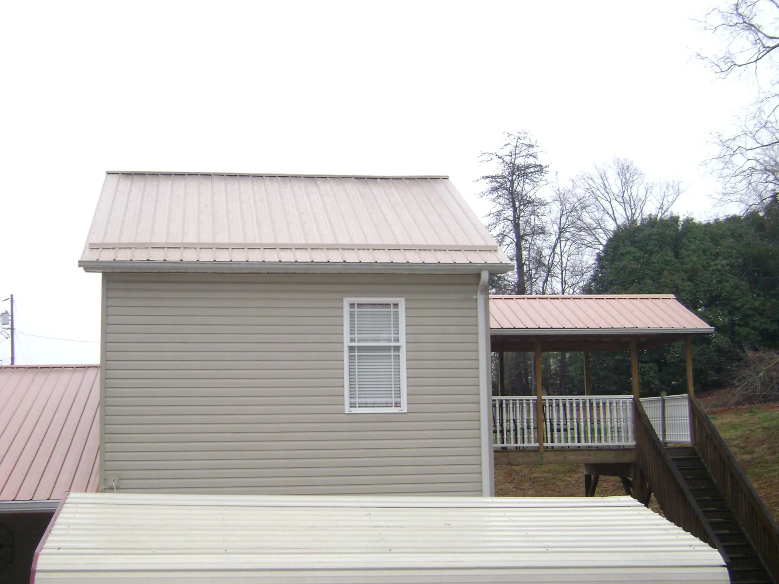 Tan metal roofs on a two story addition and attached porch, from a Roof Replacement job in Ocilla